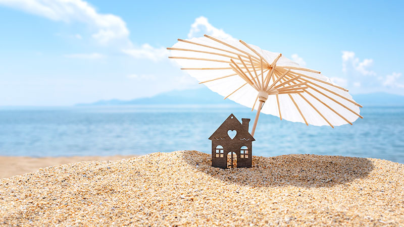 Paper house with umbrella on the beach